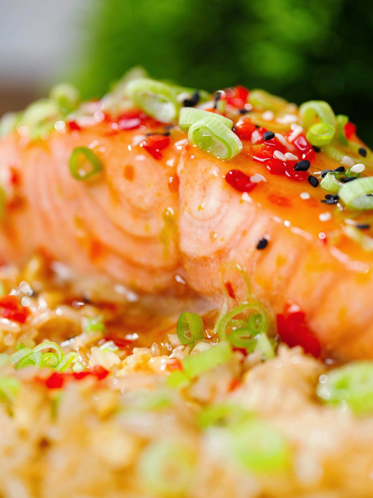 Close-up sweet chilli sauce baked salmon with egg fried rice, fresh chilli and spring onions.