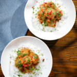 Overhead Thai red curry chicken meatballs served with white rice in two bowls.
