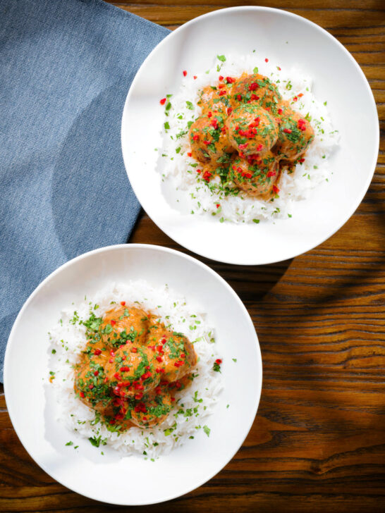 Overhead Thai red curry chicken meatballs served with white rice in two bowls.