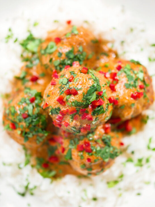 Overhead close-up Thai red curry chicken meatballs served with white rice.