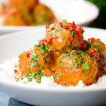 Close-up Thai red curry chicken meatballs served with white rice.