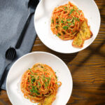 Overhead tomato and anchovy pasta served with garlic bread.