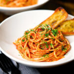 Tomato and anchovy pasta served with garlic bread.
