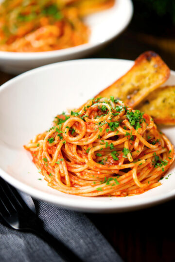 Tomato and anchovy pasta served with garlic bread.