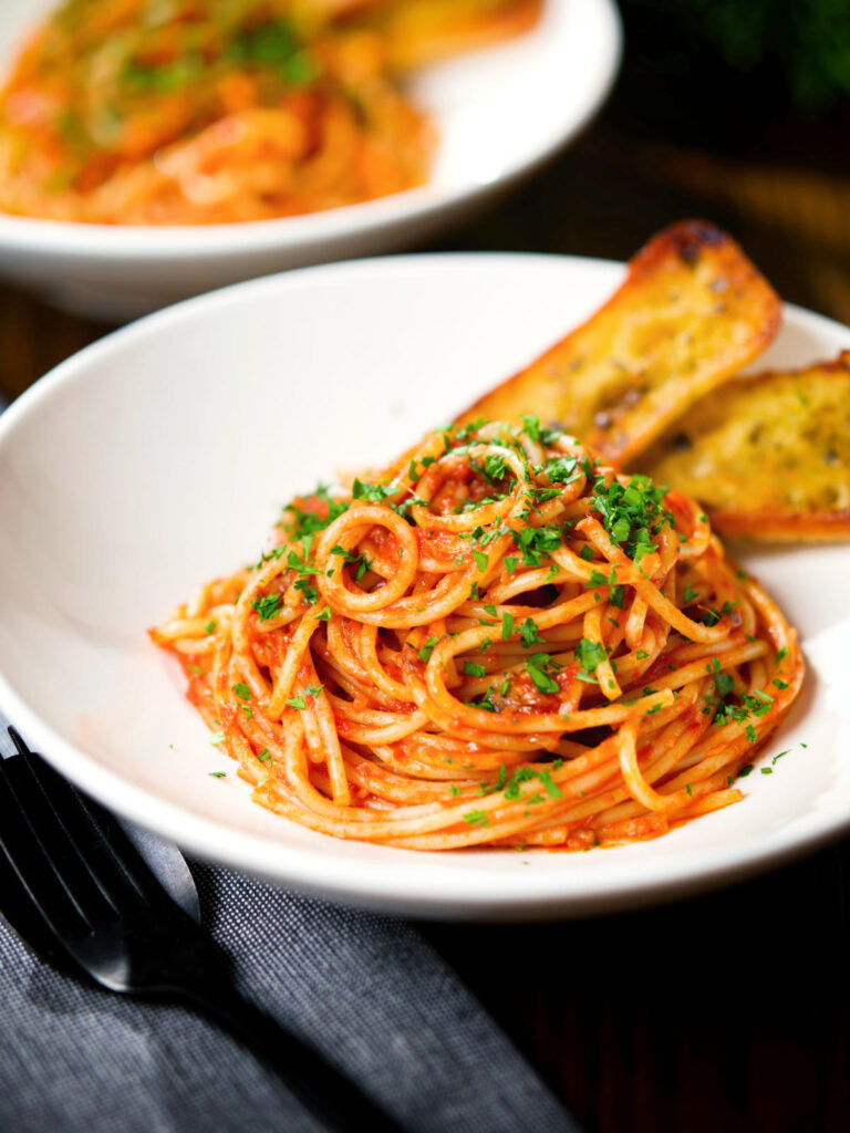 Tomato and anchovy pasta served with garlic bread.