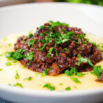 Close-up vegan mushroom ragu sauce served with creamy polenta.