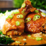 Close-up chicken adobo with coconut milk served with stir fried broccoli and rice.