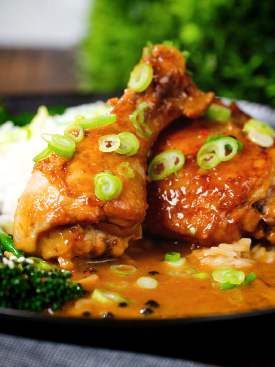 Close-up chicken adobo with coconut milk served with stir fried broccoli and rice.
