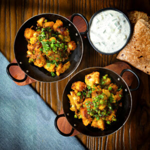 Aloo gobi matar ki sabzi: Vegan dry potato, cauliflower and pea curry served with raita and chapatis.