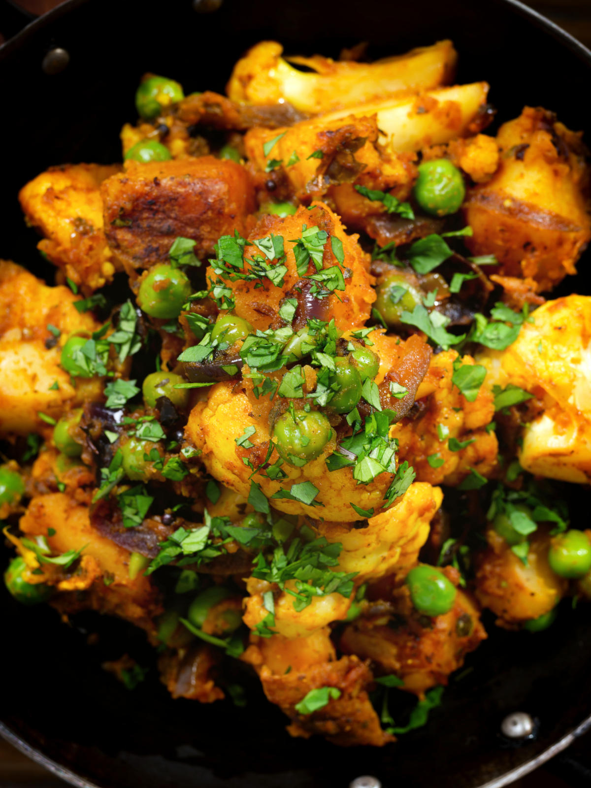 Close-up overhead Indian aloo gobi matar ki sabzi: Dry vegan potato, cauliflower and pea curry.