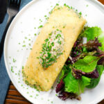 Overhead crab meat and creme fraiche stuffed omelette served with a side salad.