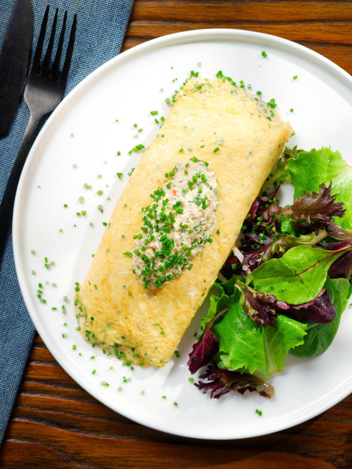 Overhead crab meat and creme fraiche stuffed omelette served with a side salad.