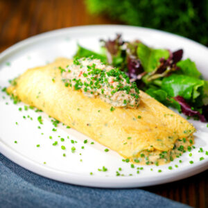 Brown and white crab meat and creme fraiche stuffed omelette served with a side salad.