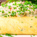Close-up crab meat and creme fraiche stuffed omelette served with a side salad.