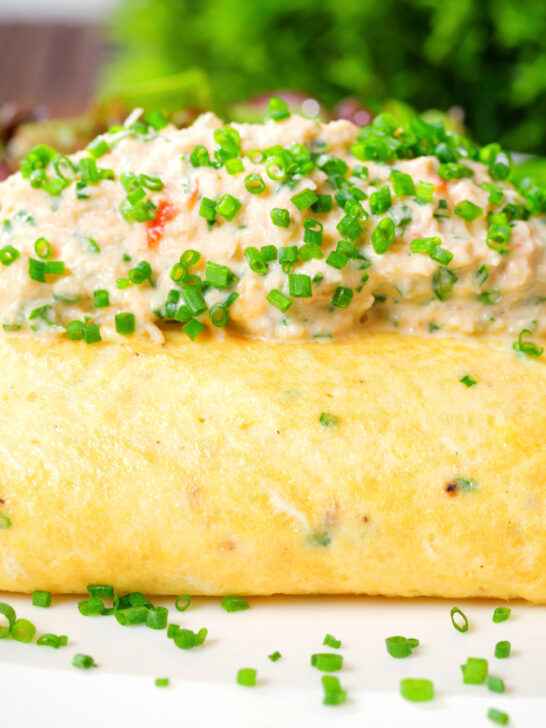 Close-up crab meat and creme fraiche stuffed omelette served with a side salad.