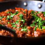 Close-up Keralan style beef curry served with fresh coriander and naan bread.