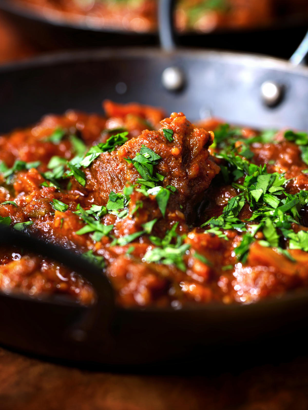 Close-up Keralan style beef curry served with fresh coriander and naan bread.