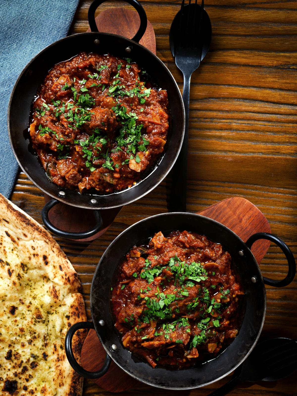 Overhead Keralan style beef curry served with fresh coriander and naan bread.