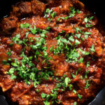 Overhead close-up Keralan style beef curry served with fresh coriander and naan bread.