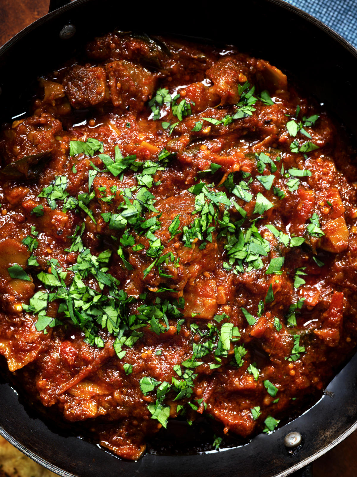 Overhead close-up Keralan style beef curry served with fresh coriander and naan bread.