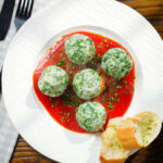 Overhead Italian Malfatti (spinach and ricotta dumplings) with tomato sauce and garlic bread.