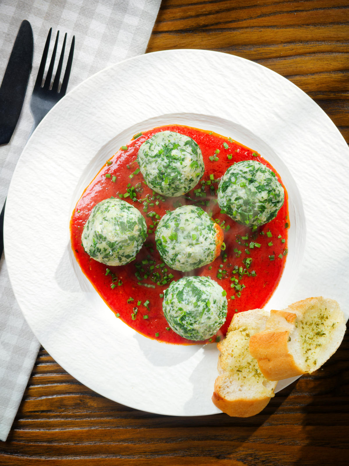 Overhead Italian Malfatti (spinach and ricotta dumplings) with tomato sauce and garlic bread.