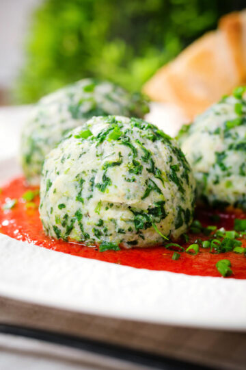 Close-up Italian Malfatti (spinach and ricotta dumplings) with tomato sauce and garlic bread.