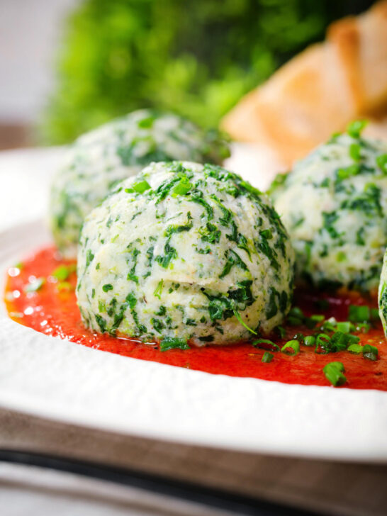 Close-up Italian Malfatti (spinach and ricotta dumplings) with tomato sauce and garlic bread.