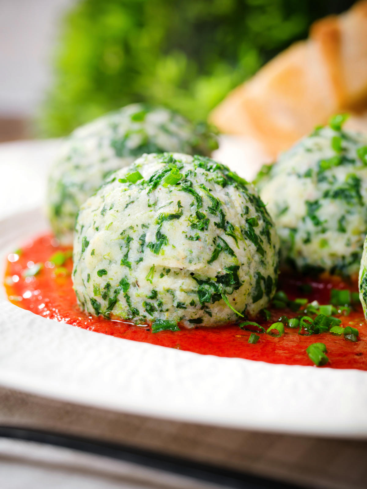 Close-up Italian Malfatti (spinach and ricotta dumplings) with tomato sauce and garlic bread.