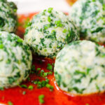 Close-up Italian Malfatti (spinach and ricotta dumplings) with tomato sauce, chives and garlic bread.