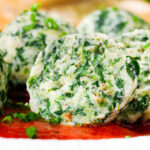Cut open Italian Malfatti (spinach and ricotta dumplings) with tomato sauce and garlic bread.