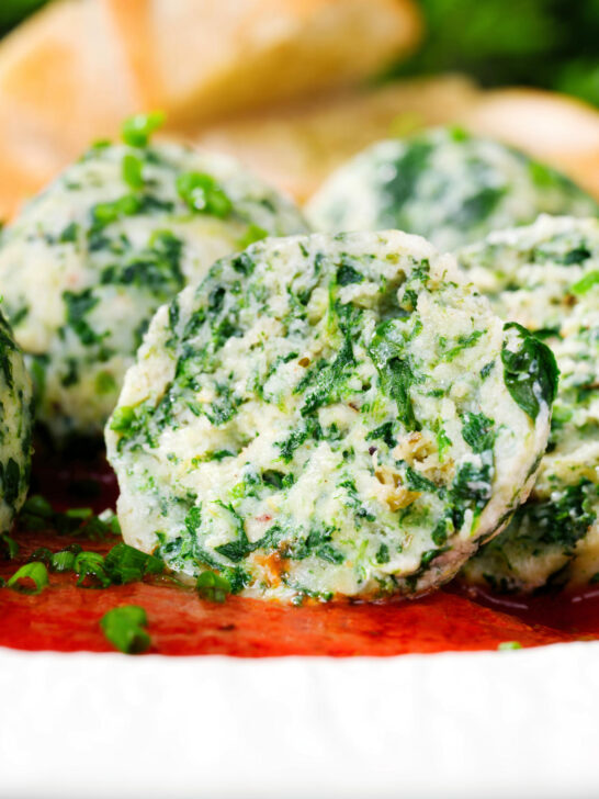 Cut open Italian Malfatti (spinach and ricotta dumplings) with tomato sauce and garlic bread.