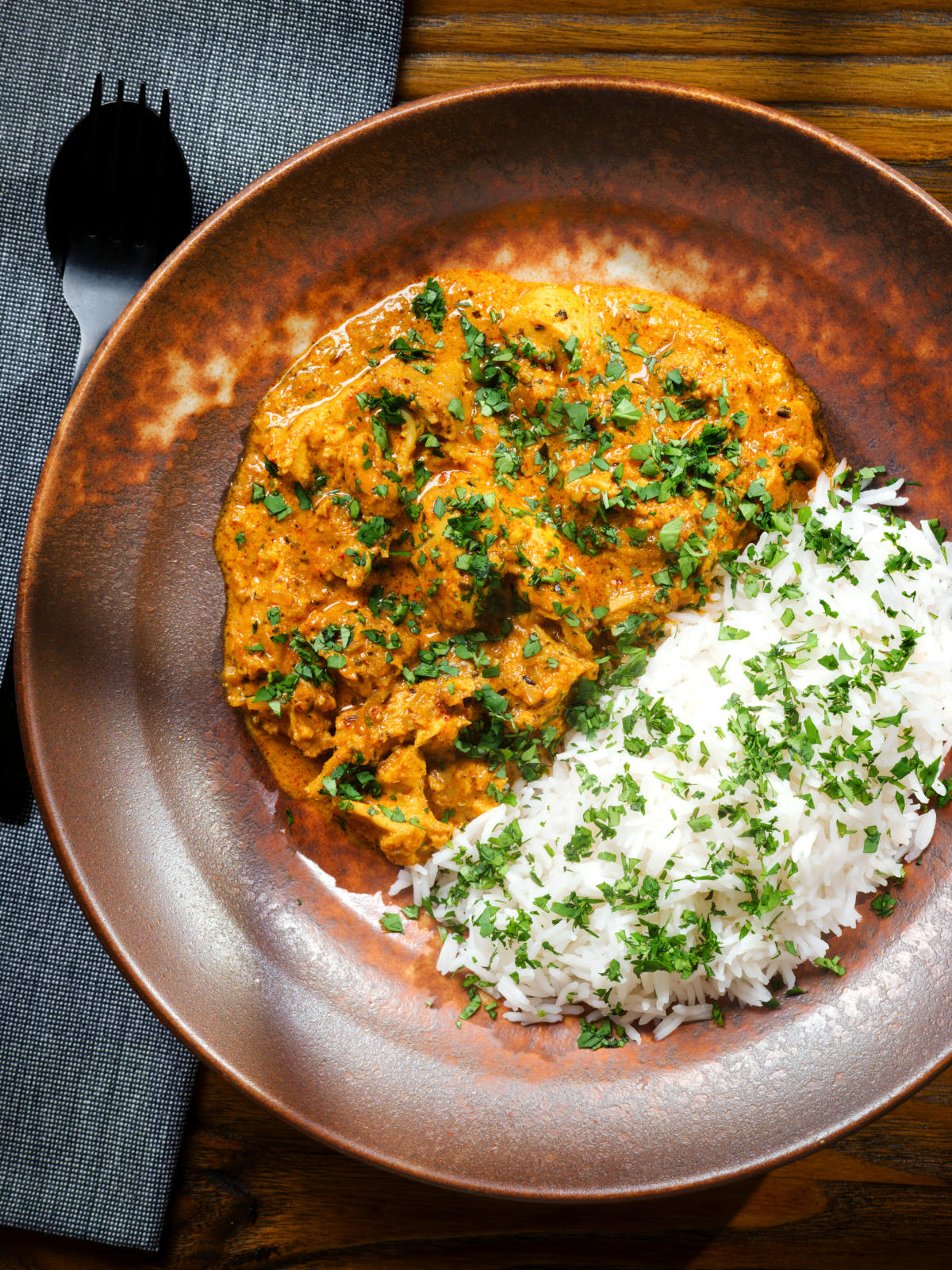 Overhead Indian nawabi chicken curry with basmati rice and coriander.