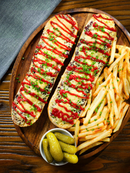 Overhead Polish cheese and mushroom zapiekanka open sandwich served with ketchup and fries.