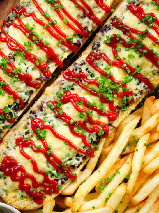 Overhead close-up Polish cheese and mushroom zapiekanka open sandwich served with ketchup and fries.
