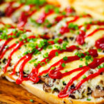 Close-up Polish cheese and mushroom zapiekanka open sandwich served with ketchup and fries.