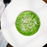 Overhead risotto verde with spinach, green peas and broad beans.