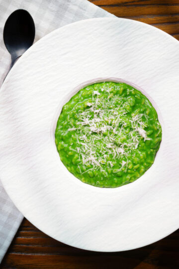 Overhead risotto verde with spinach, green peas and broad beans.