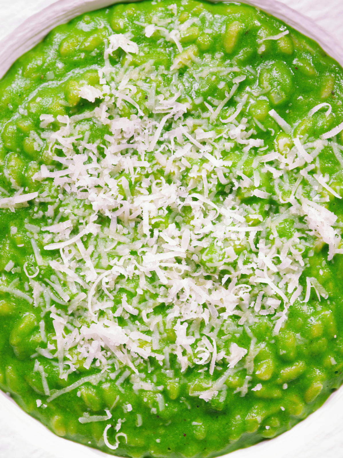 Close-up overhead risotto verde with spinach, green peas and broad beans.