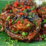 Close-up vegan mushroom rendang curry served with rice, fresh chilli and coriander.