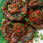 Overhead close-up vegan mushroom rendang curry served with rice, fresh chilli and coriander.