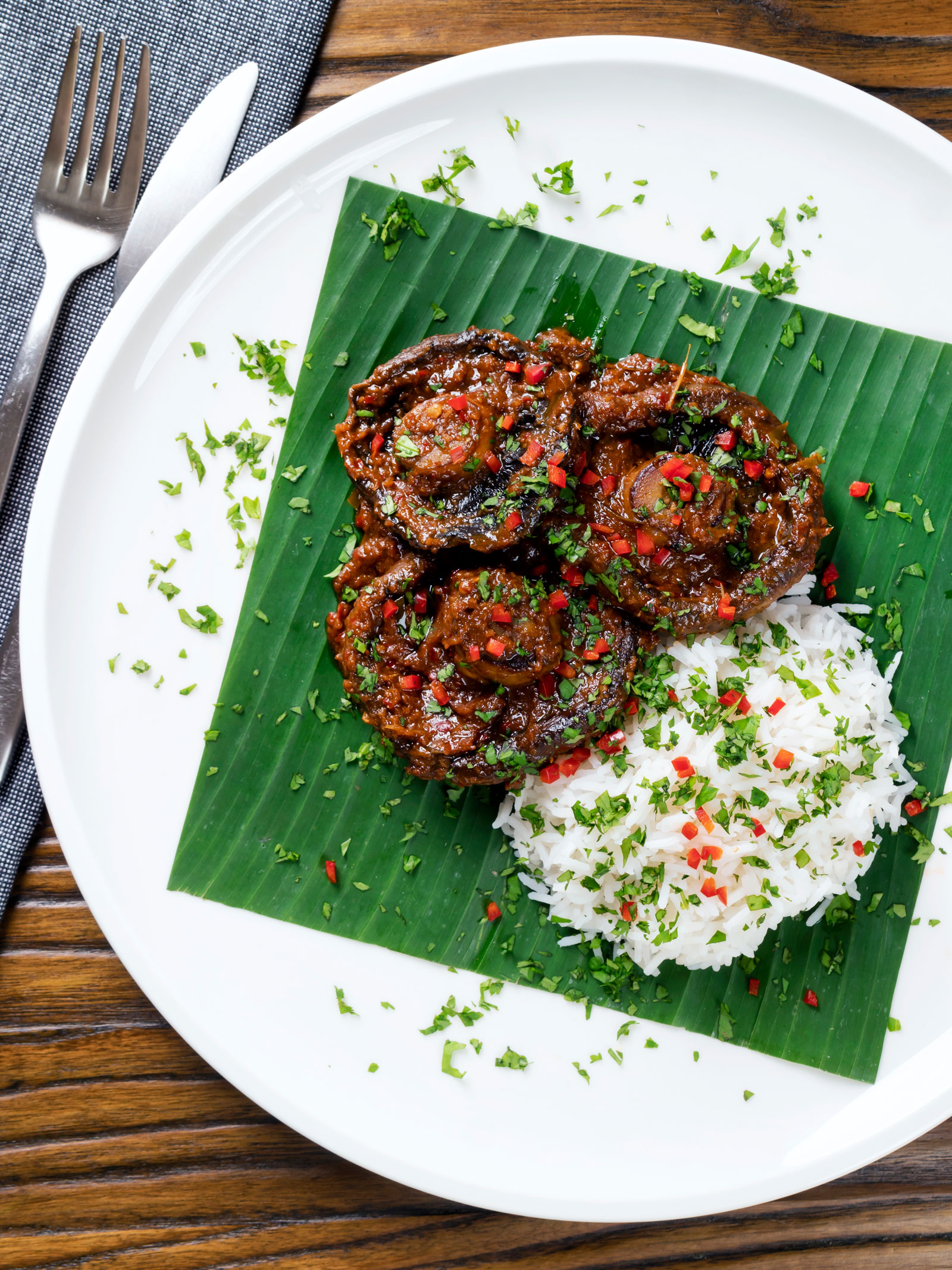 Overhead vegan mushroom rendang curry served with rice, fresh chilli and coriander.