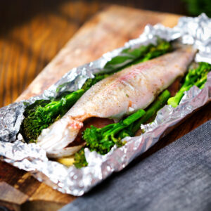 Whole baked fish (rainbow trout) cooked in foil with asparagus and tenderstem broccoli.