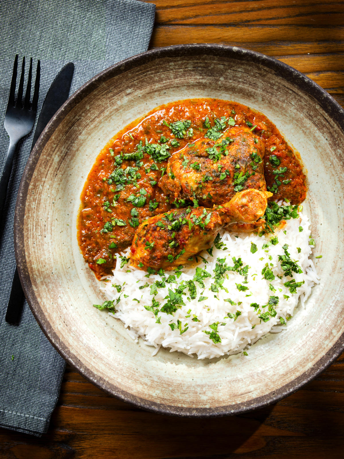 Overhead Indian chicken kolhapuri curry served with rice and coriander.