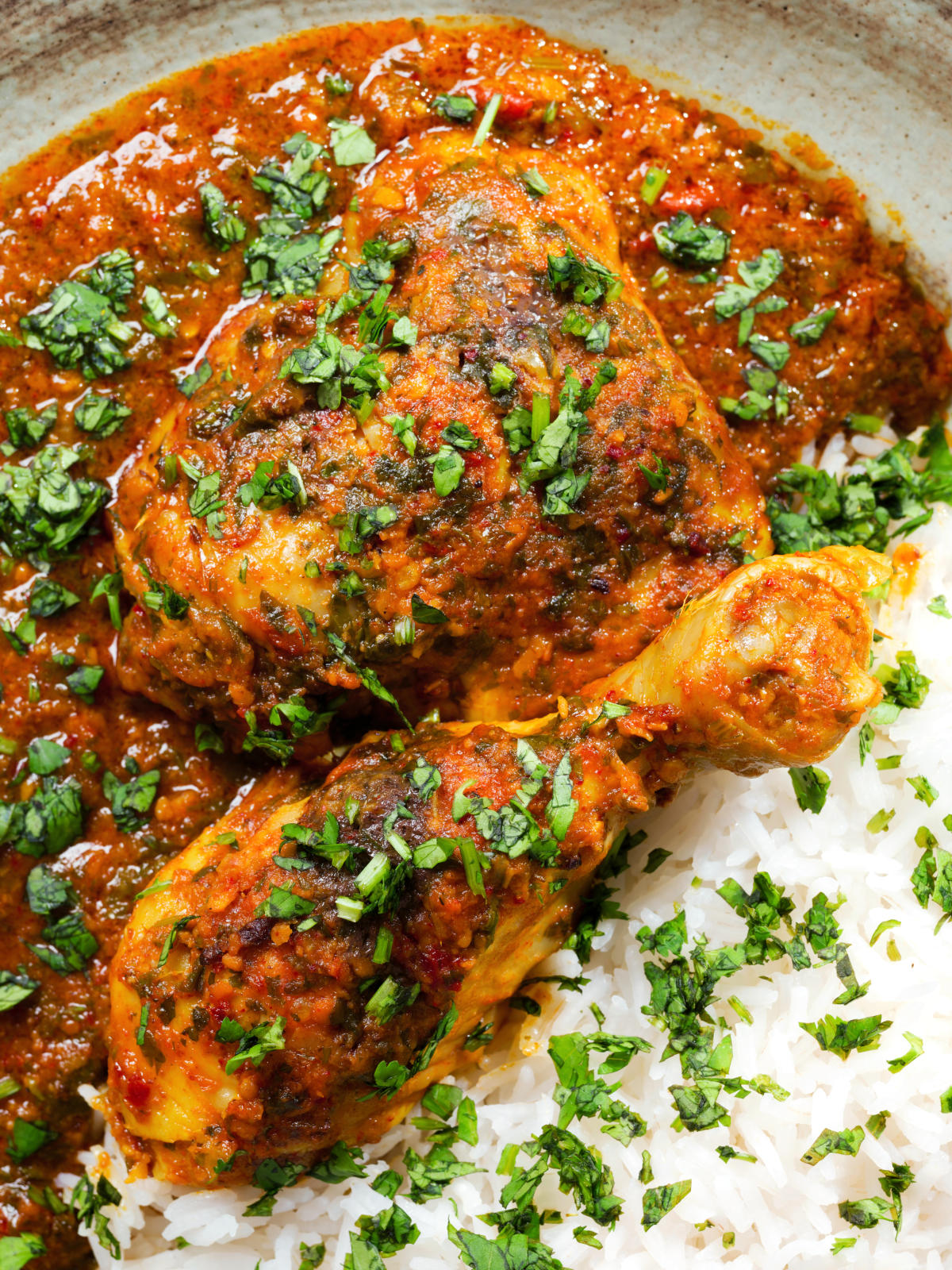 Close-up overhead Indian chicken kolhapuri curry served with rice and coriander.
