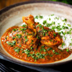 Indian chicken kolhapuri curry served with rice and coriander.