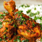 Close-up Indian chicken kolhapuri curry served with rice and coriander.
