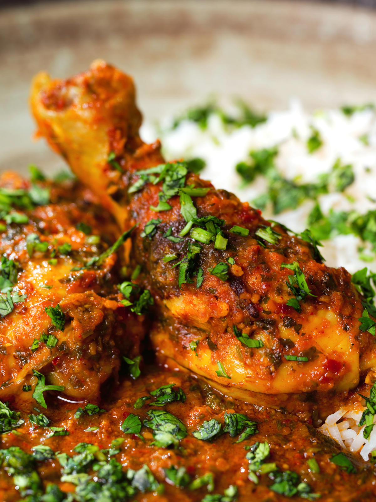 Close-up Indian chicken kolhapuri curry served with rice and coriander.