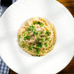 Overhead lemon and caper chicken piccata pasta (malfadine) garnished with fresh parsley.