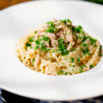 Lemon and caper chicken piccata pasta (malfadine) garnished with fresh parsley.